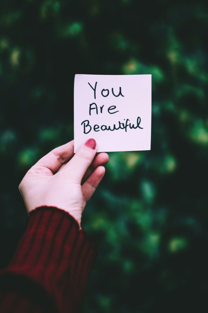 A person holding up a note that says you are beautiful.